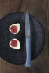 Couteau Bon Appétit+ anthracite sur une assiette noire avec des figues