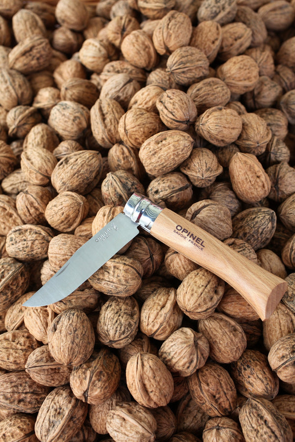 Couteau Opinel N°08 hêtre posé sur un lit de noix
