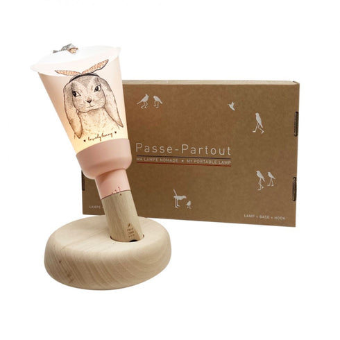 Lampe Passe-Partout Lapin so Sweet rose poudré sur son socle en hêtre, devant son coffret