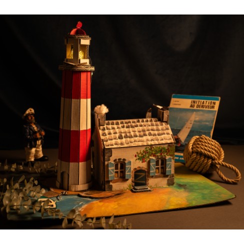 Maquette du phare peinte en rouge et blanc, dans un décor marin
